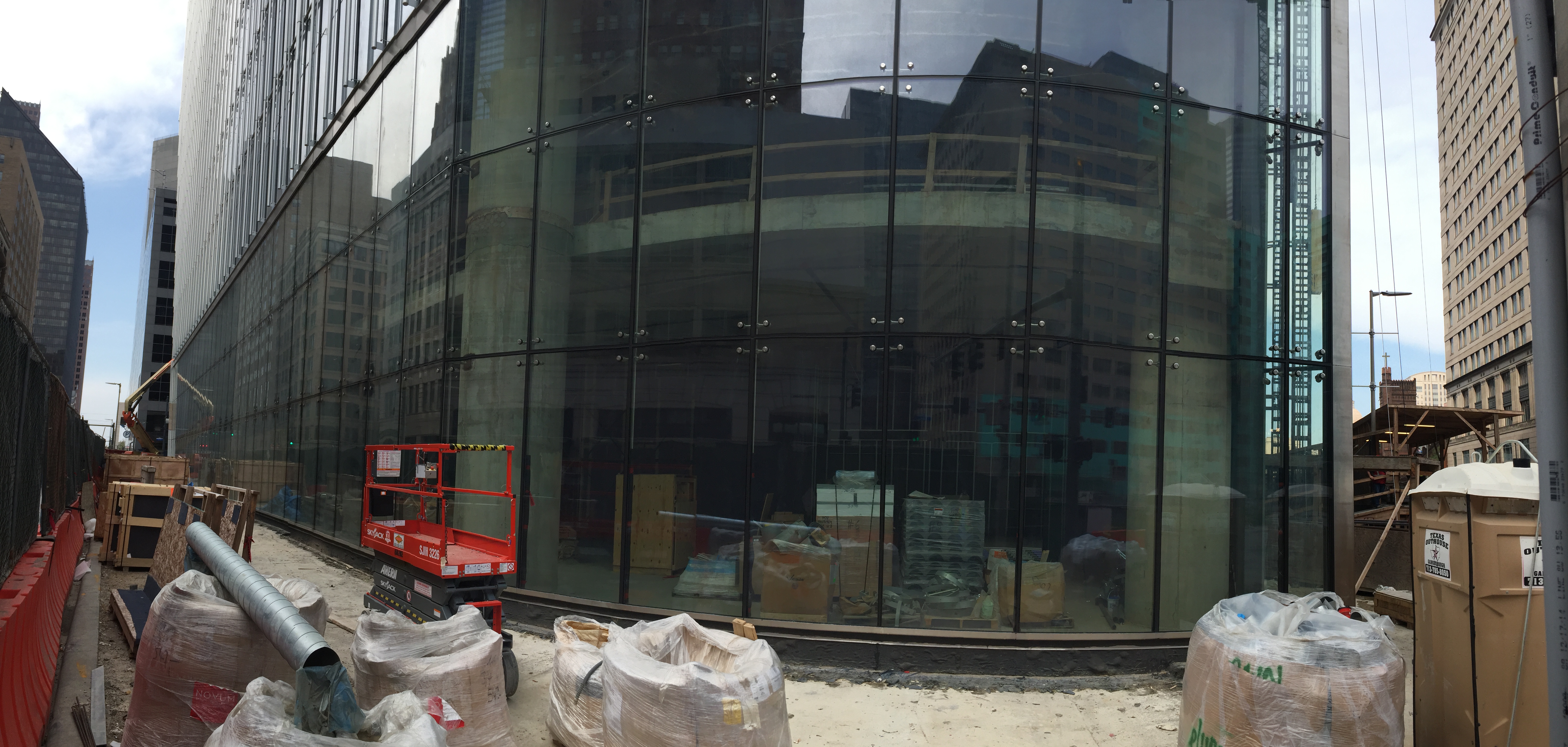 Construction site with glass building and bags of materials.