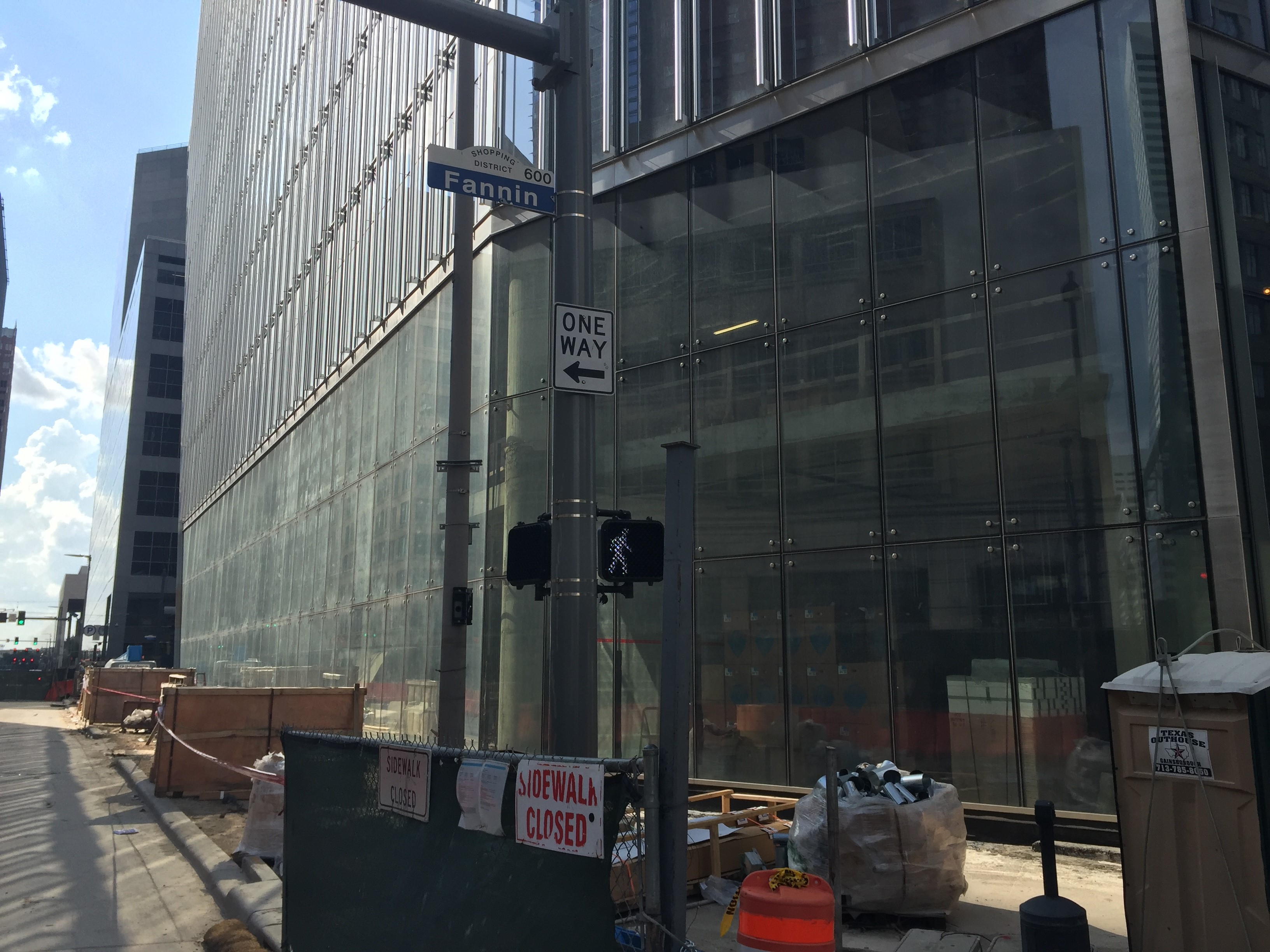 Construction site with glass building and scaffolding on a city street.