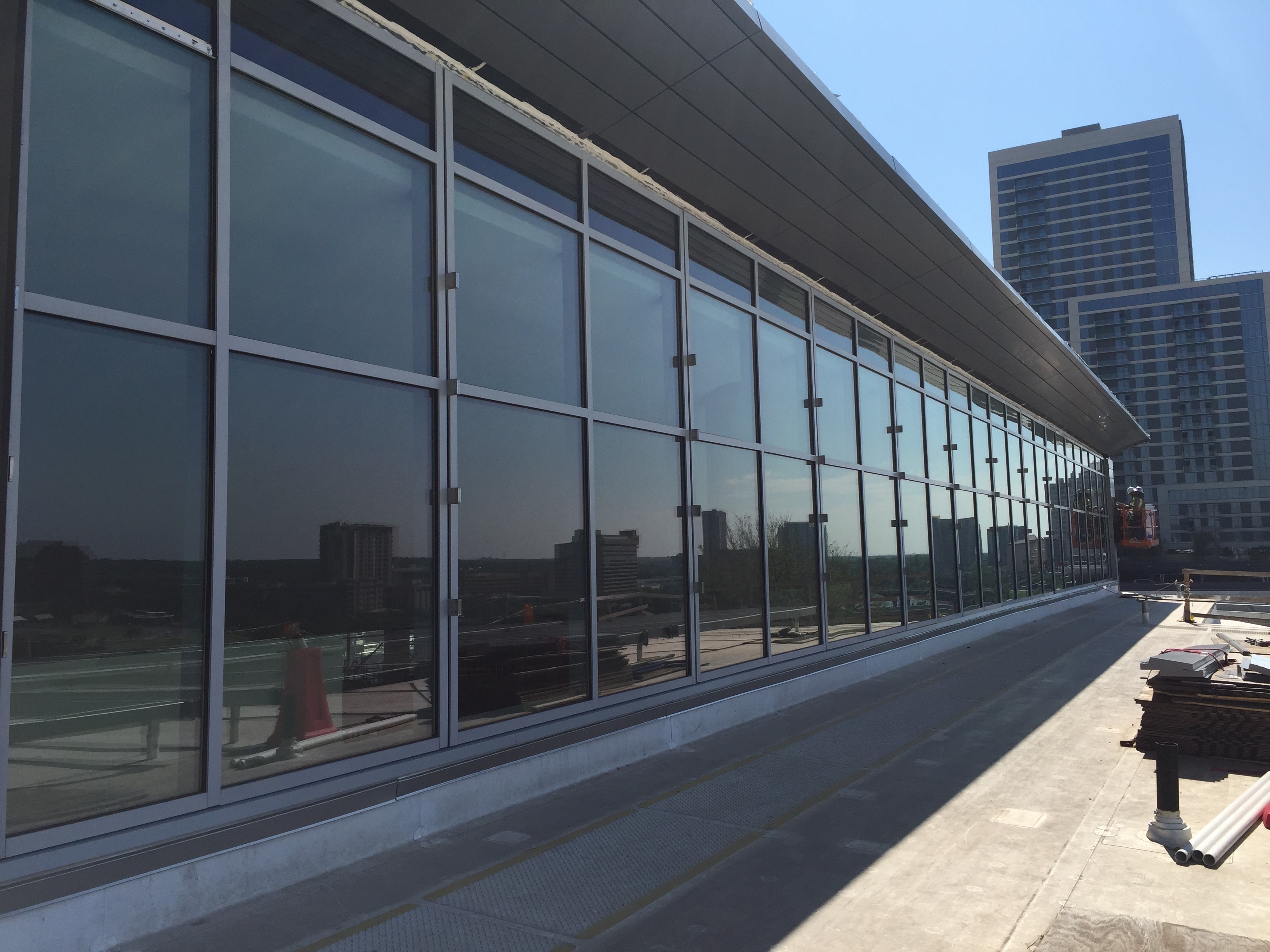 Modern building with reflective glass windows along a sidewalk under clear blue sky.