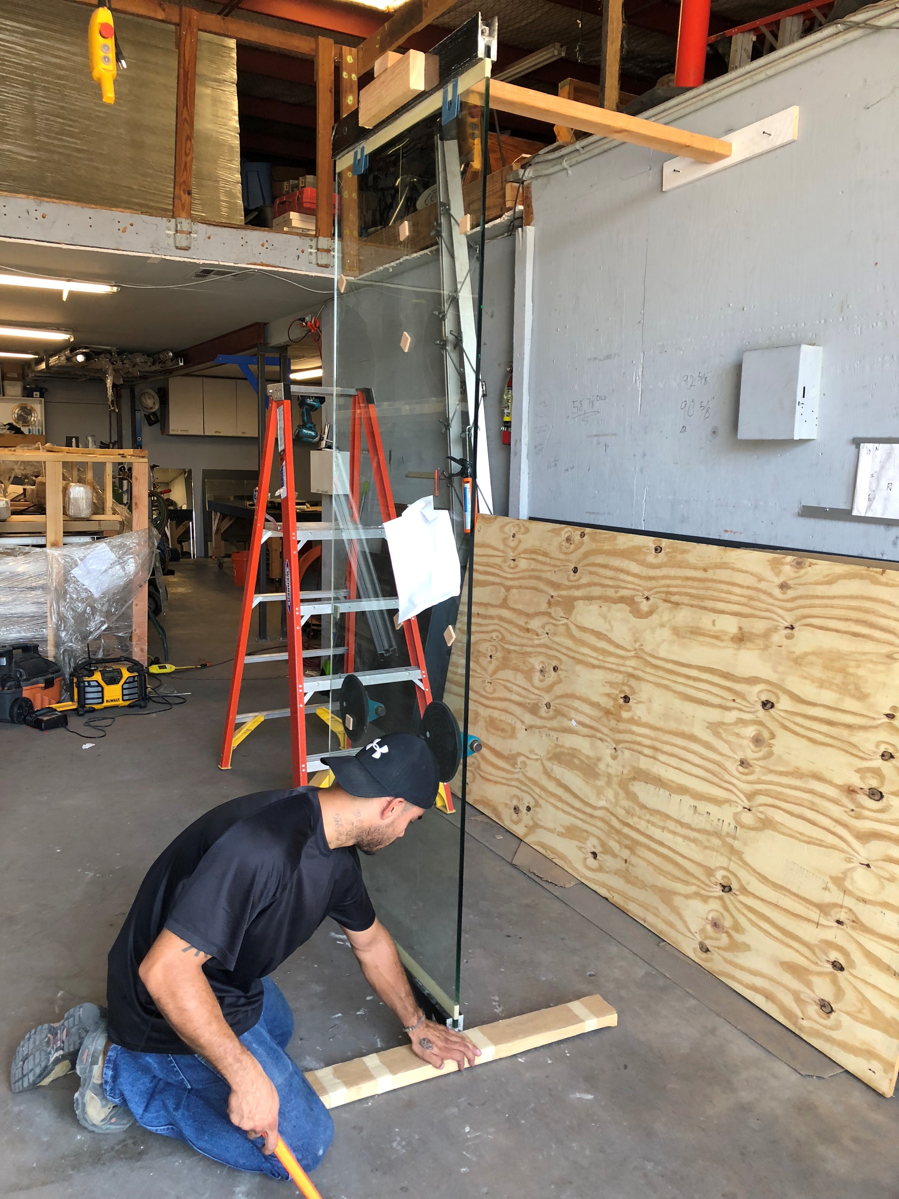 Man installing wooden paneling on a wall inside a workshop.