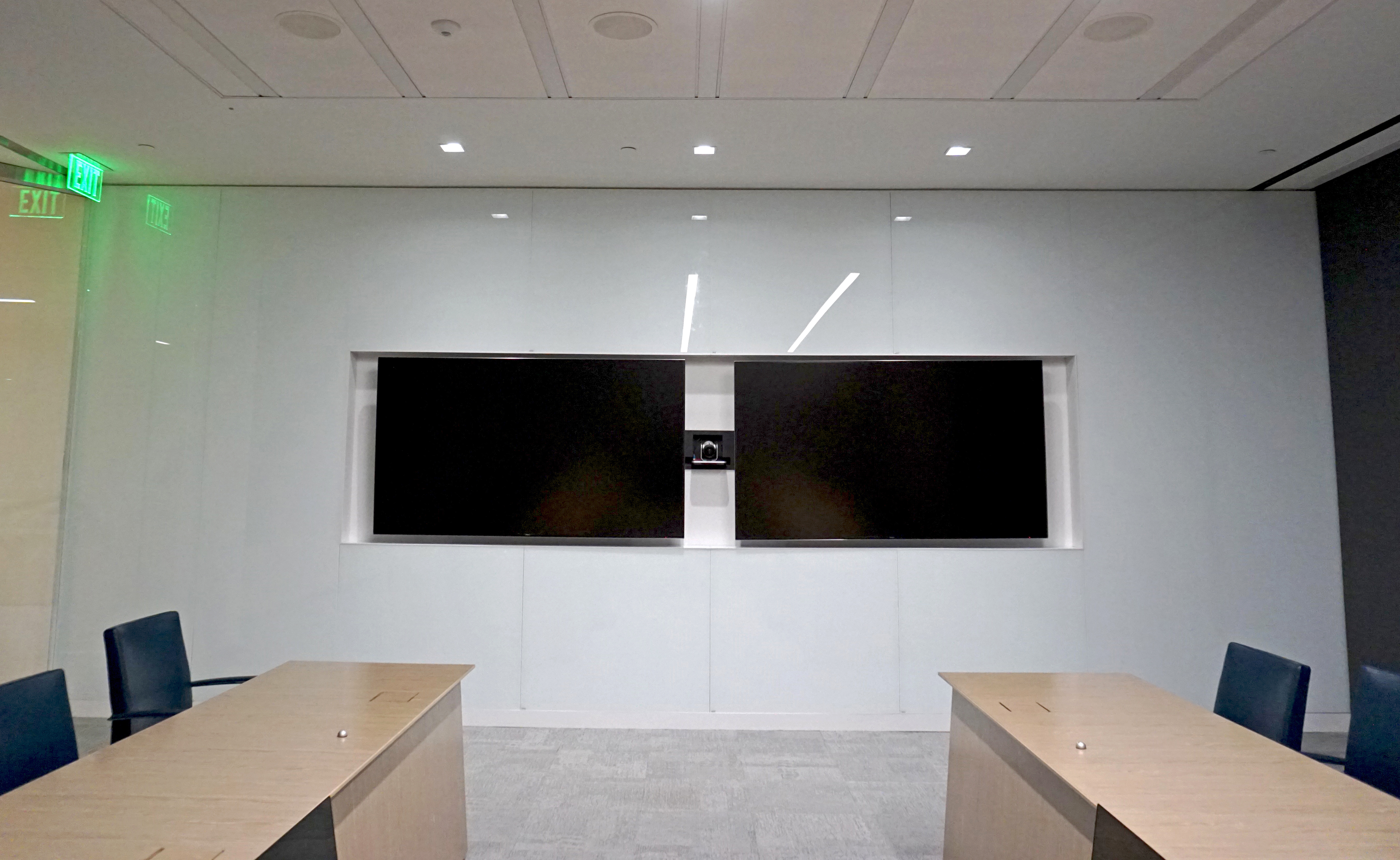 Modern conference room with two large screens and a white wall.
