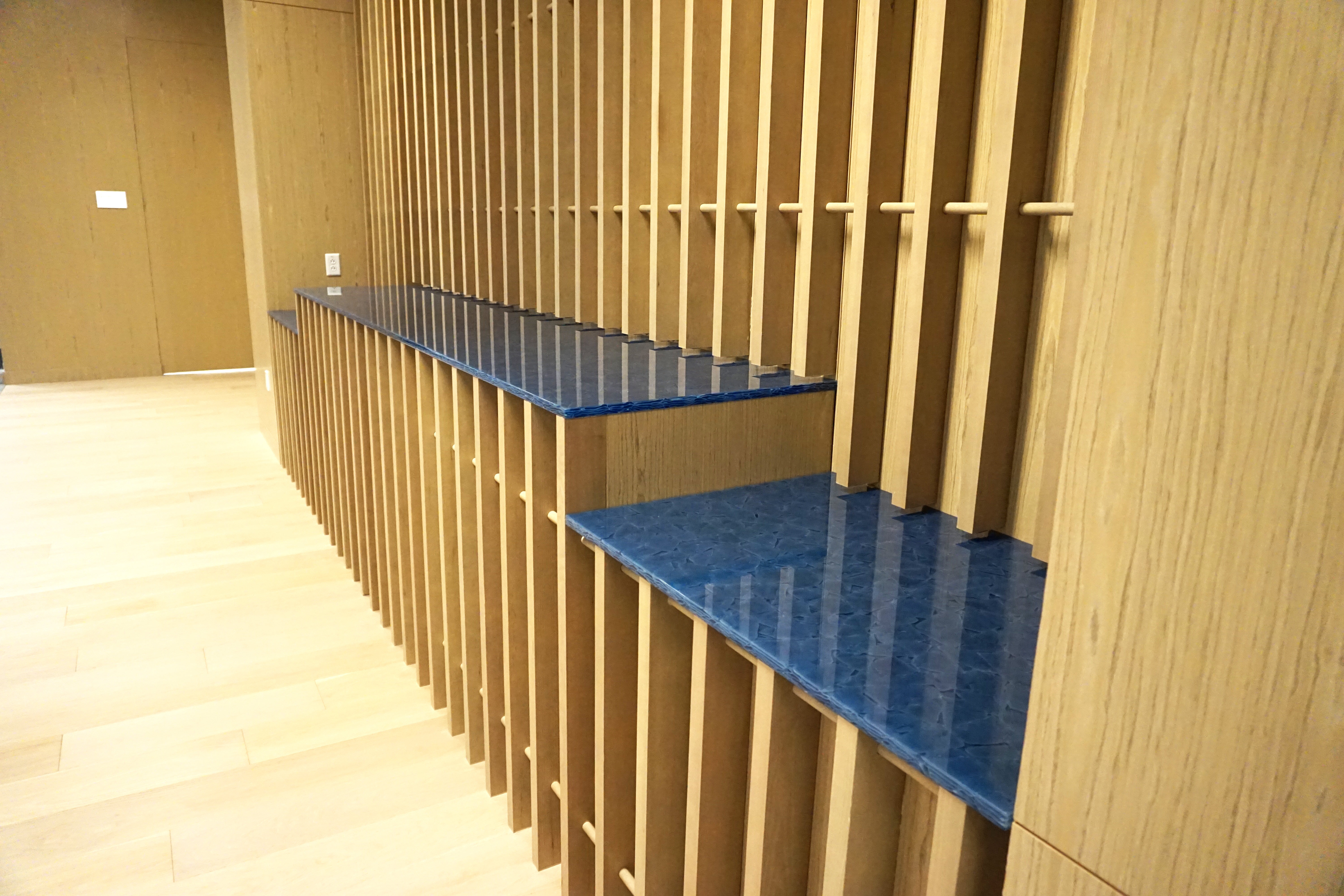 Blue textured shelves mounted on a vertical wooden slat wall.