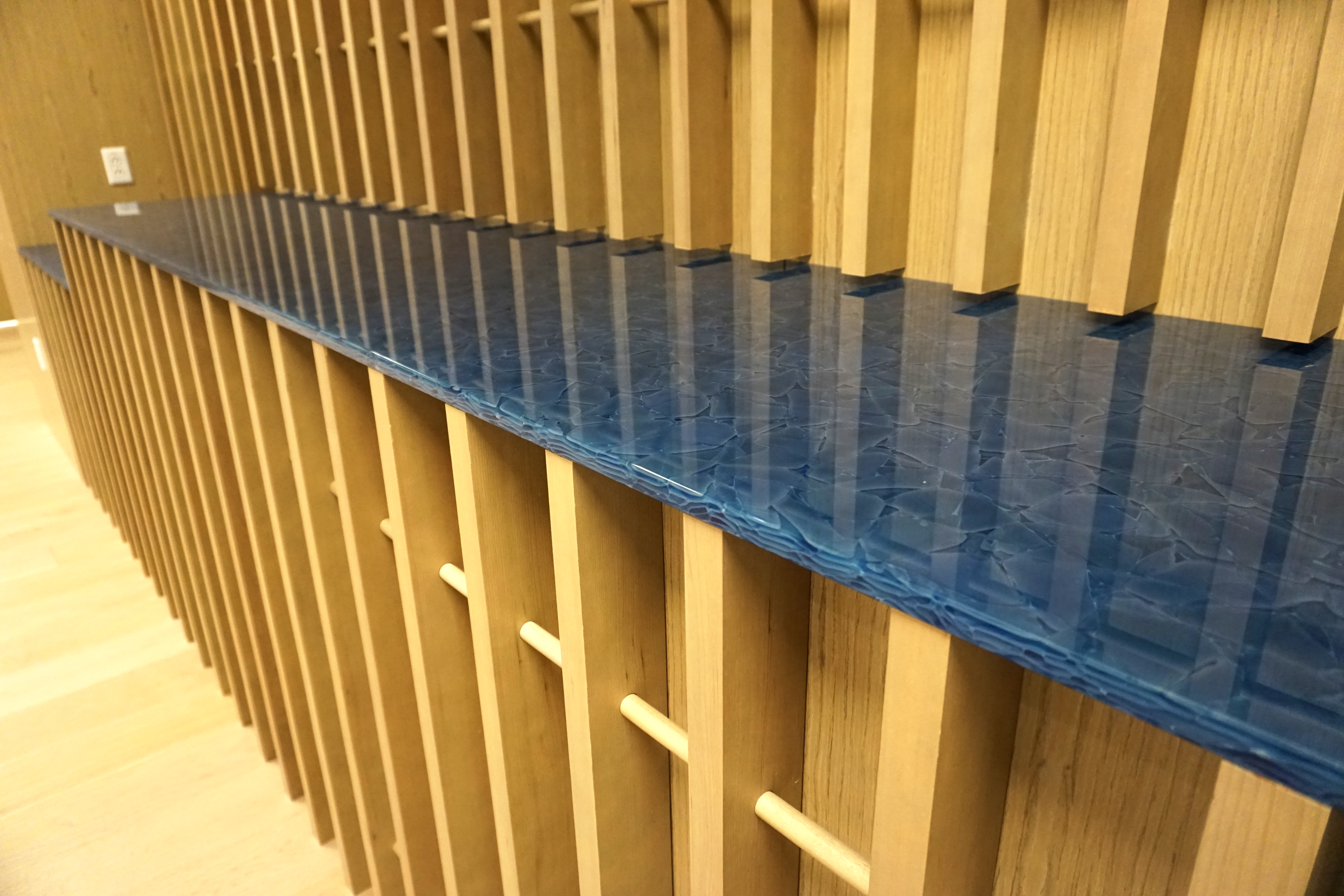 Blue glass shelf mounted on a yellow wooden frame with vertical slats.