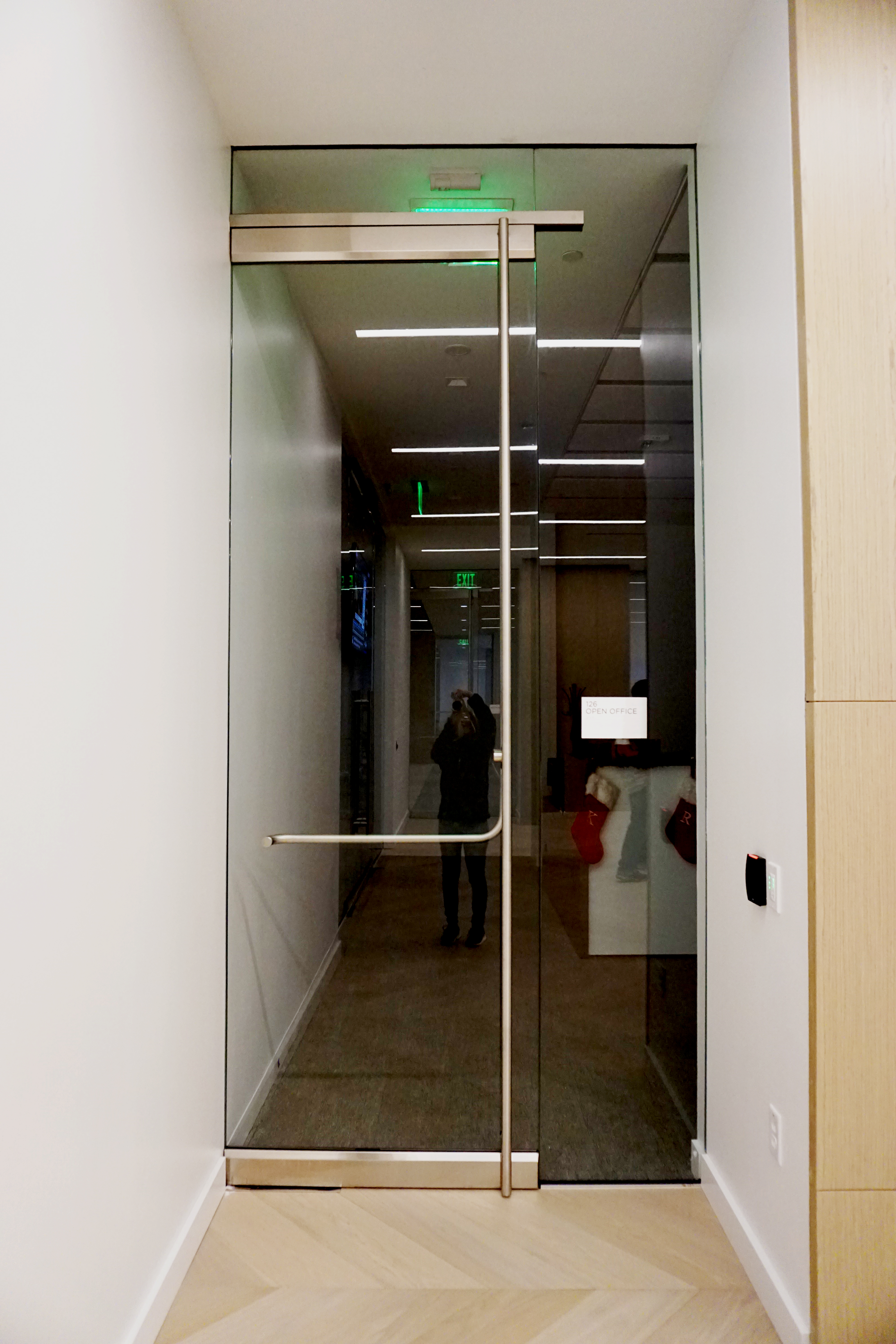 Reflection of a person in a glass door at an office corridor.