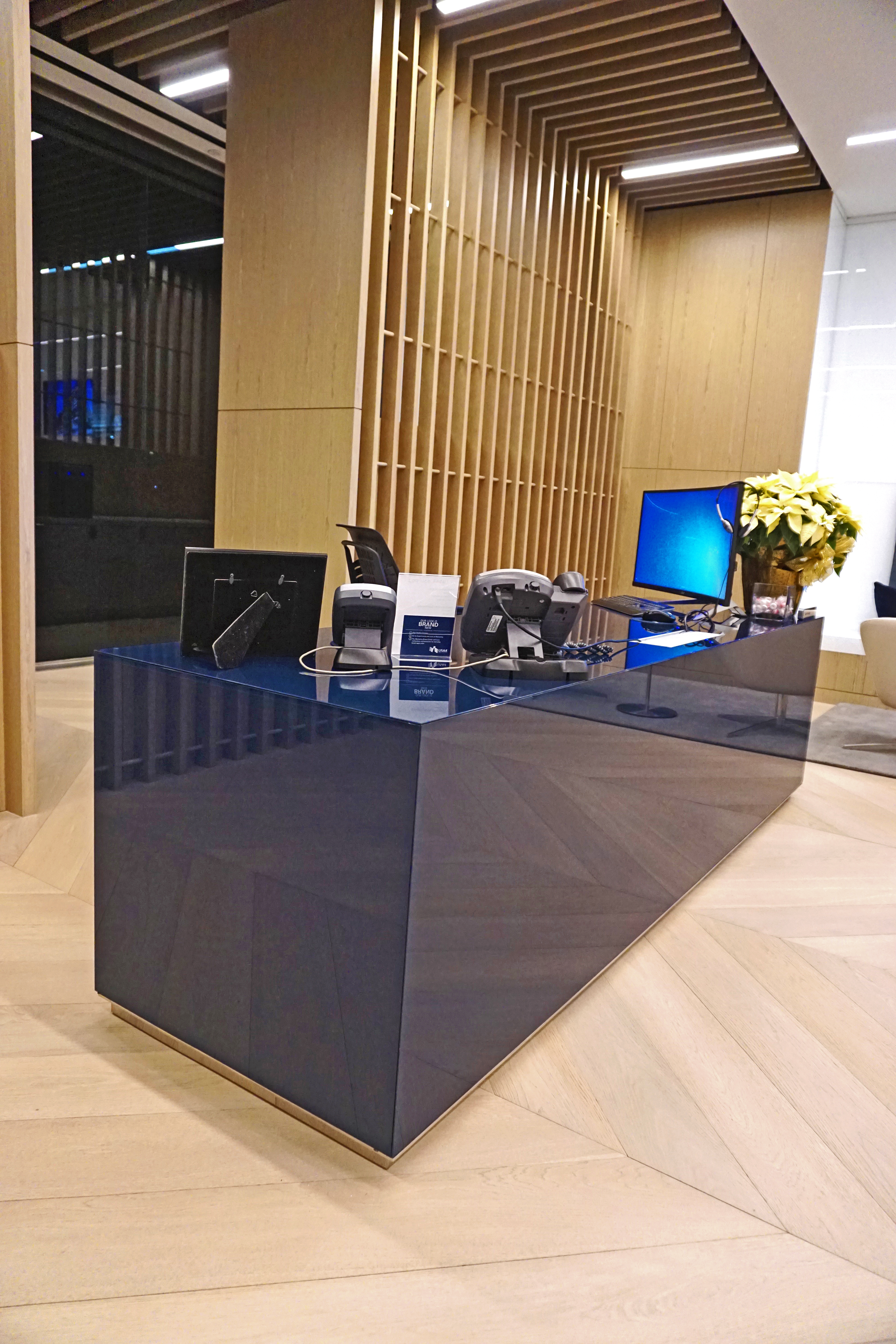 Modern office desk with computer and flowers in a well-lit room.