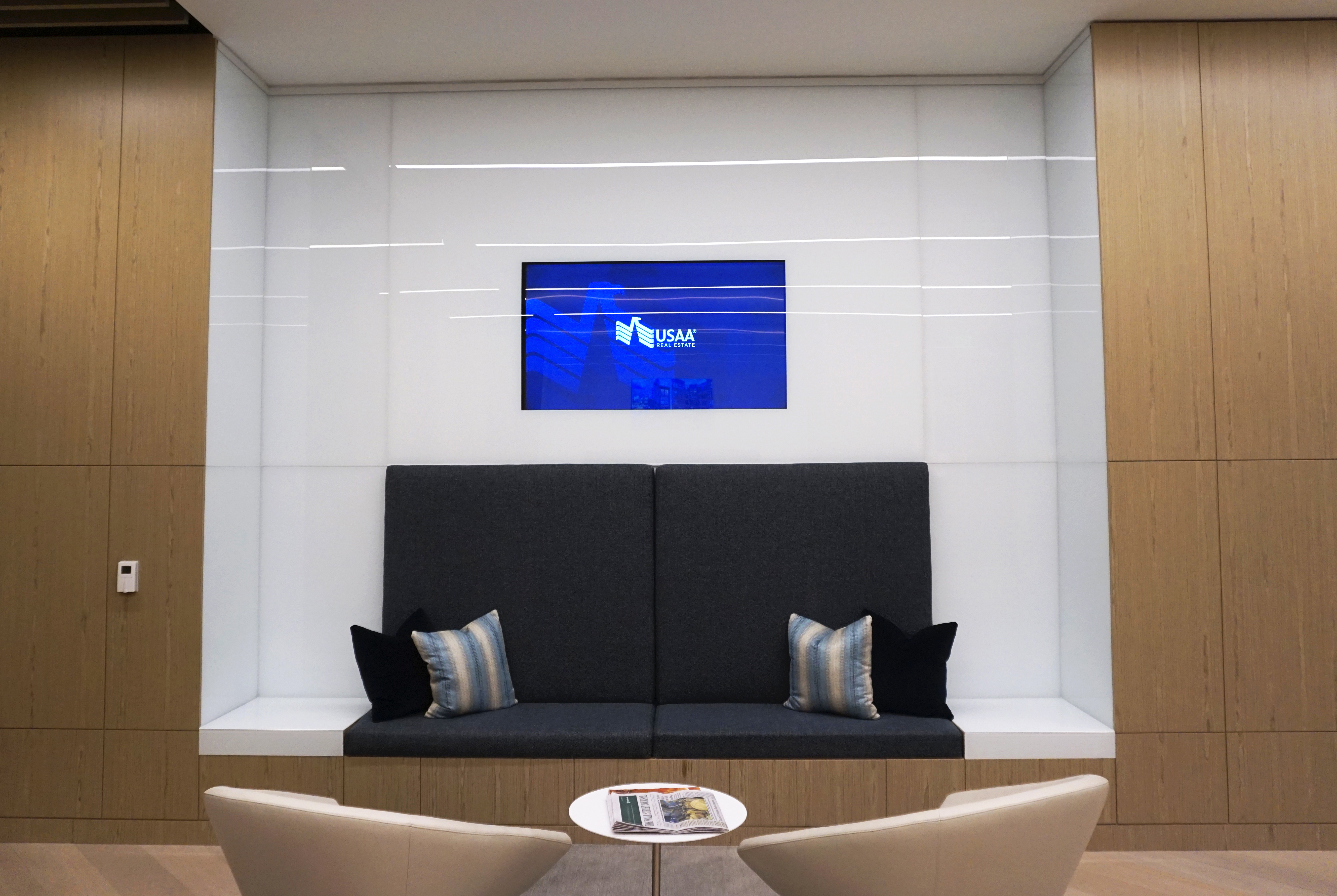 Modern waiting area with sleek black seating and a blue screen on the wall.