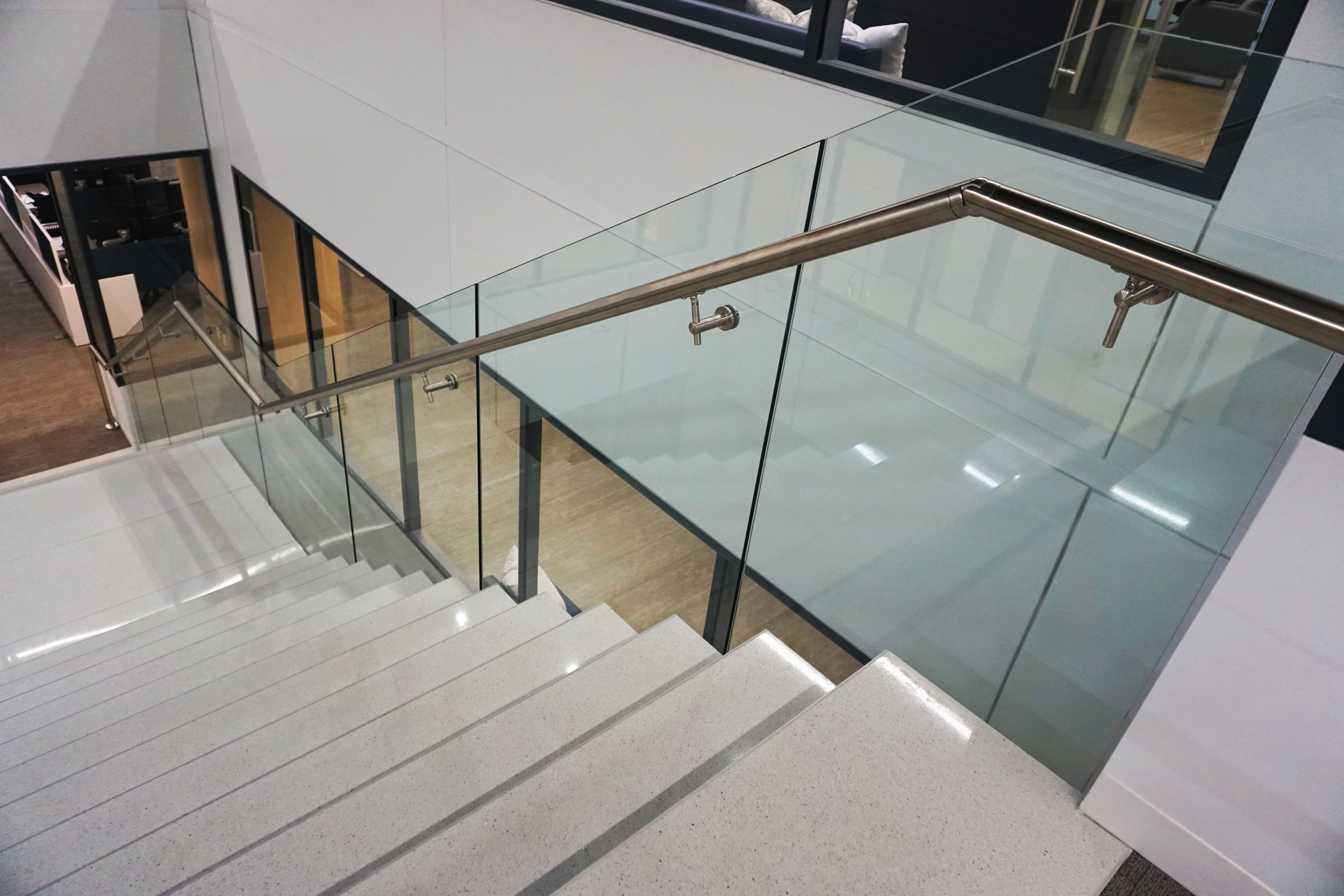 Modern staircase with glass railing and sleek metal handrail.