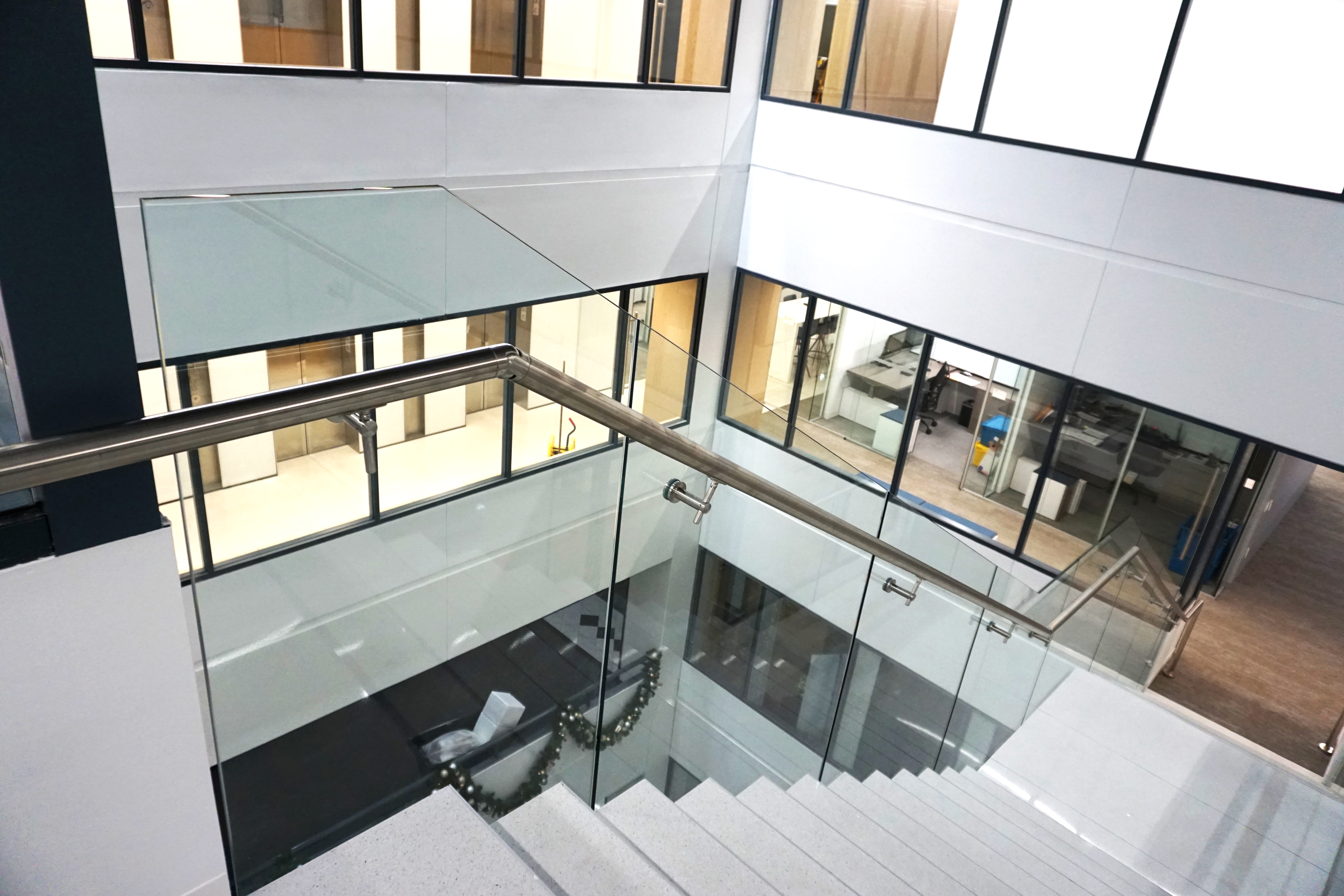 Modern staircase with glass railing inside a bright office building.