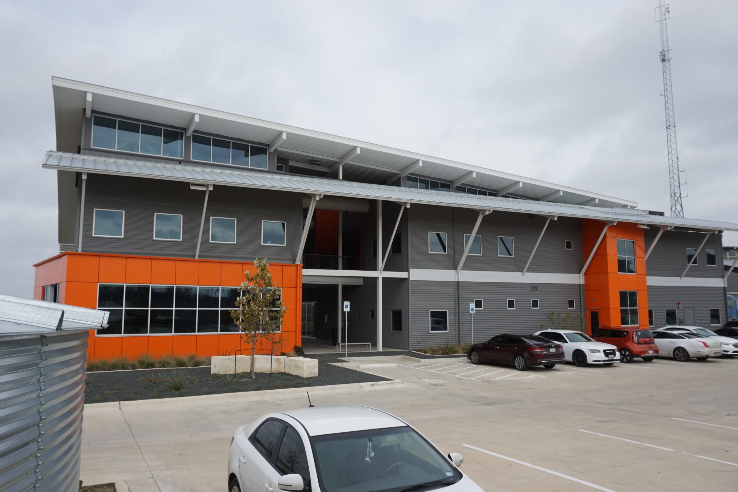 Modern commercial building with parking lot and overcast sky.