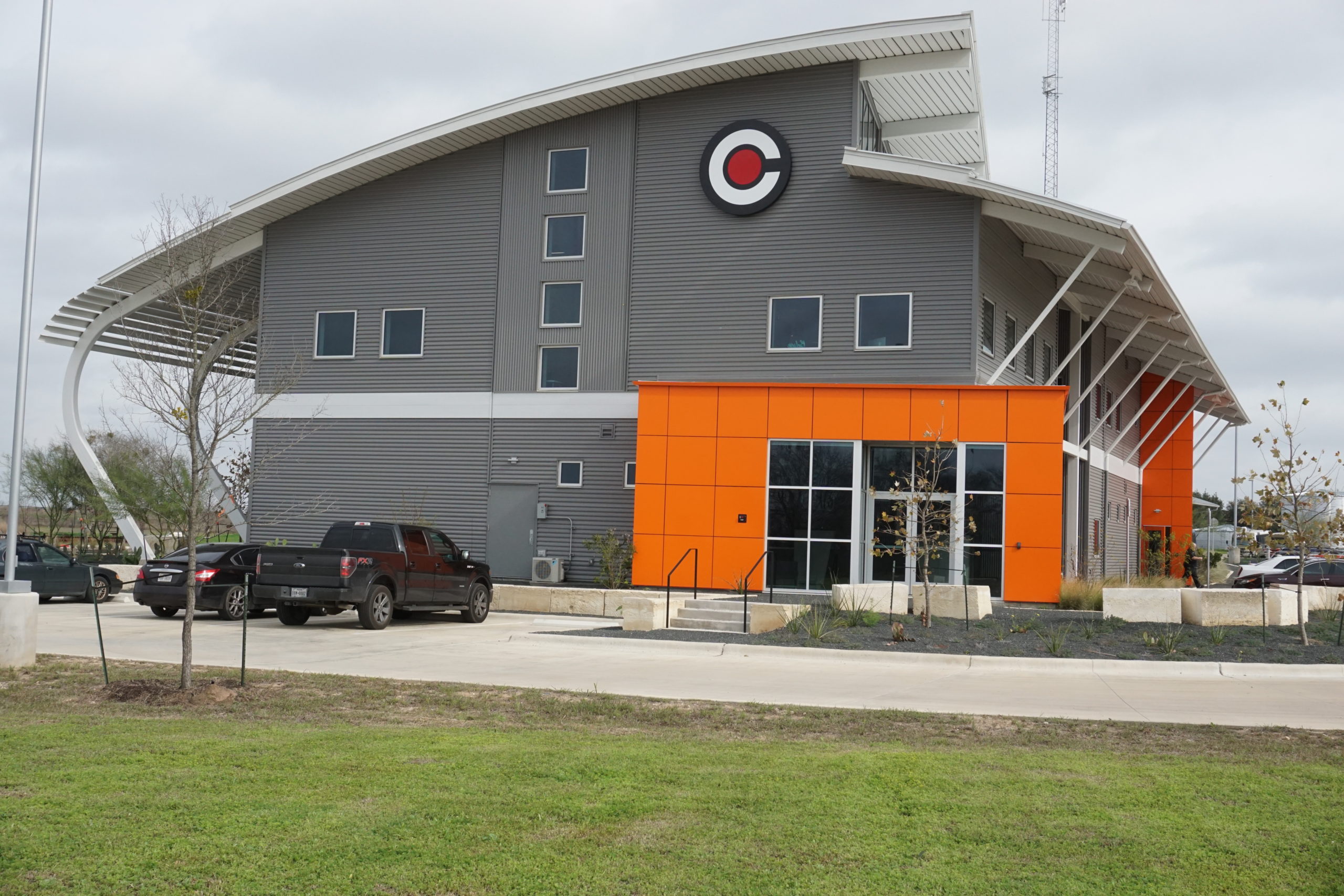 Modern building with gray walls and an orange accent near the entrance.