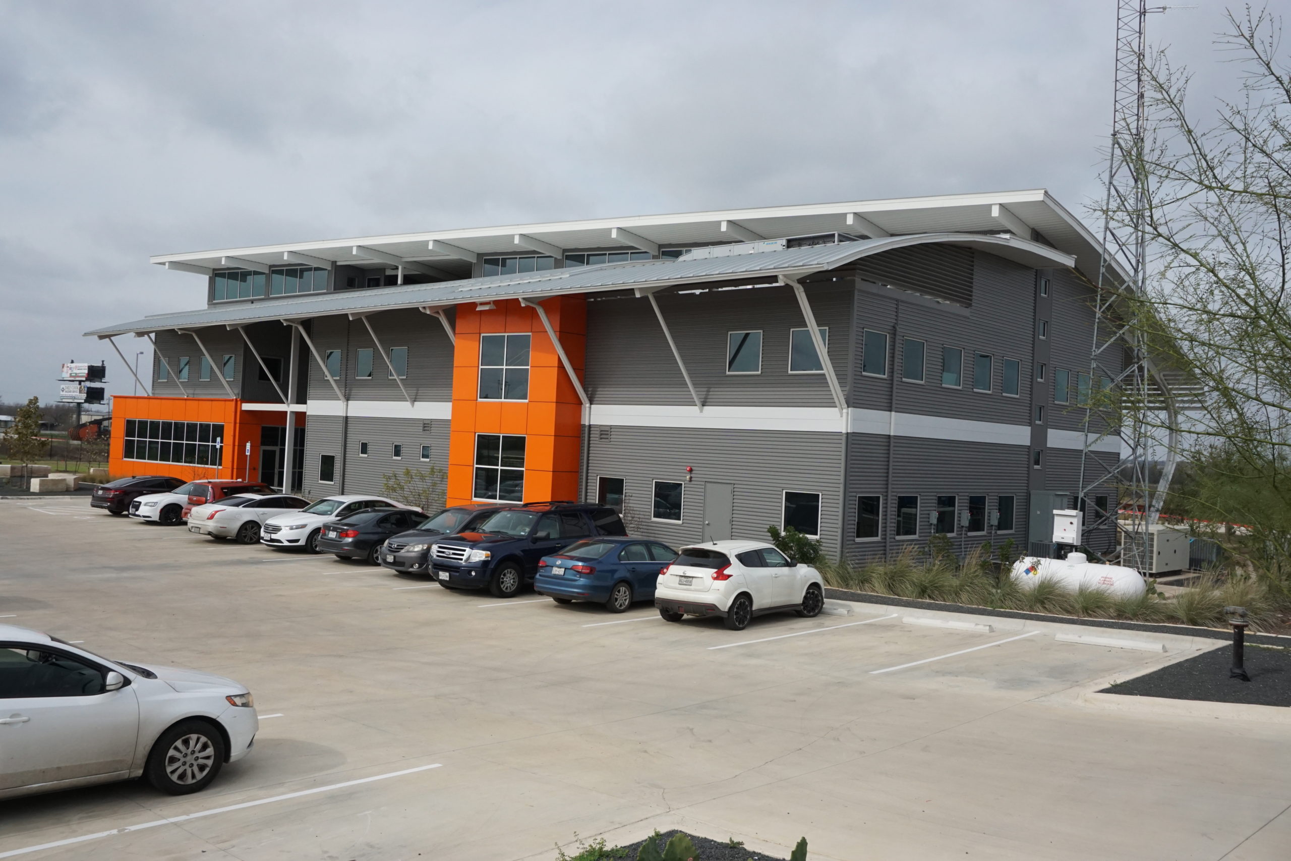 Modern commercial building with parked cars in front.